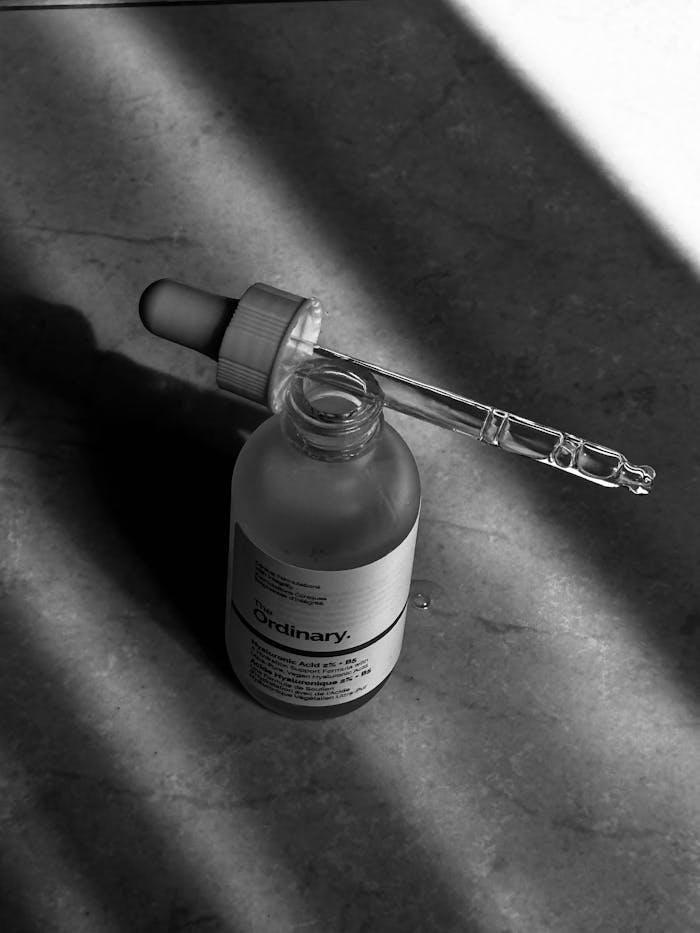 gallery-1 Elegant black and white photo of a skincare serum bottle with dropper in morning light shadows.